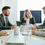 Confident young blond female coach in formalwear sitting in front of audience